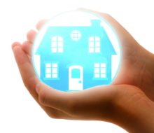 A person's hand embracing a blue ball with a house within, reaffirming their sense of belonging.