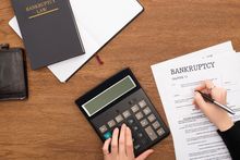 A person completing a bankruptcy form on a desk with a calculator, seeking assistance from bankruptcy lawyers in New York City.