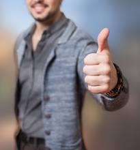 A man is giving a thumbs up in front of a blurred background. (Keywords: man, thumbs up)